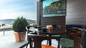 Ein moderner Essbereich mit Panoramablick auf die Stadt, einem Bild an der Wand und einer Kaffeemaschine.