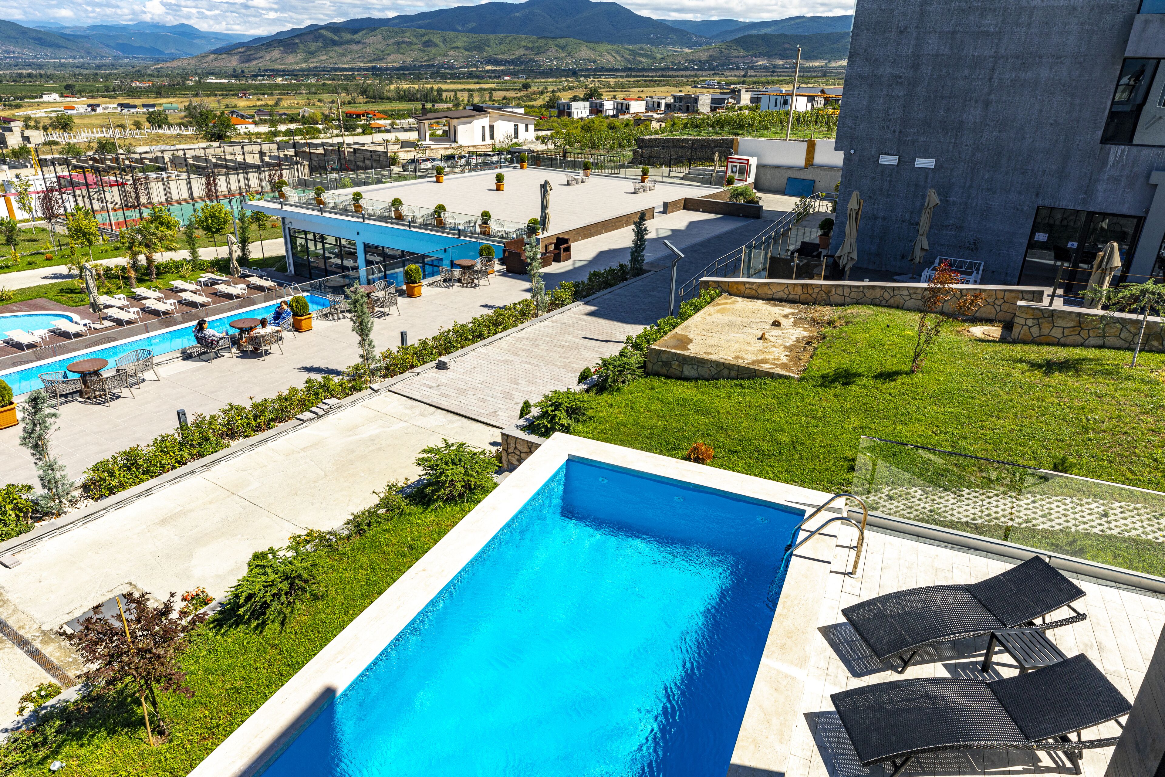 Un área de piscina en la azotea con sillones de descanso, una piscina y vistas del paisaje circundante.