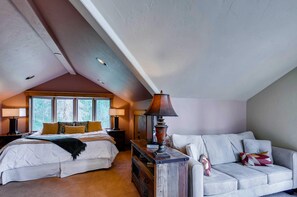 Een slaapkamer met een bed, nachtkastje, lamp, dressoir en een bank.