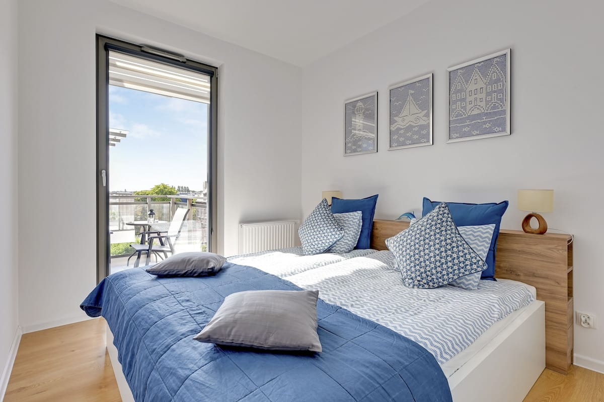 A bedroom with a large bed, a wooden headboard, and a view of the outdoors through a sliding door.