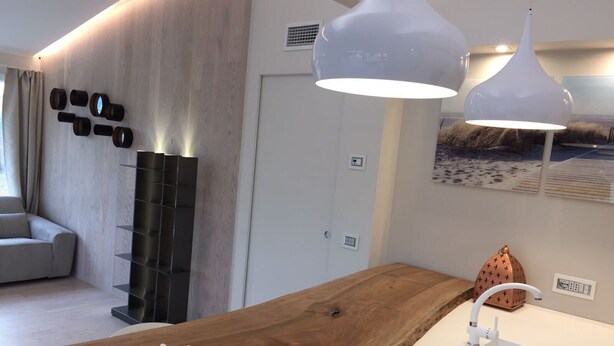 Una cocina moderna con encimera de madera, pileta blanca e iluminación colgante.