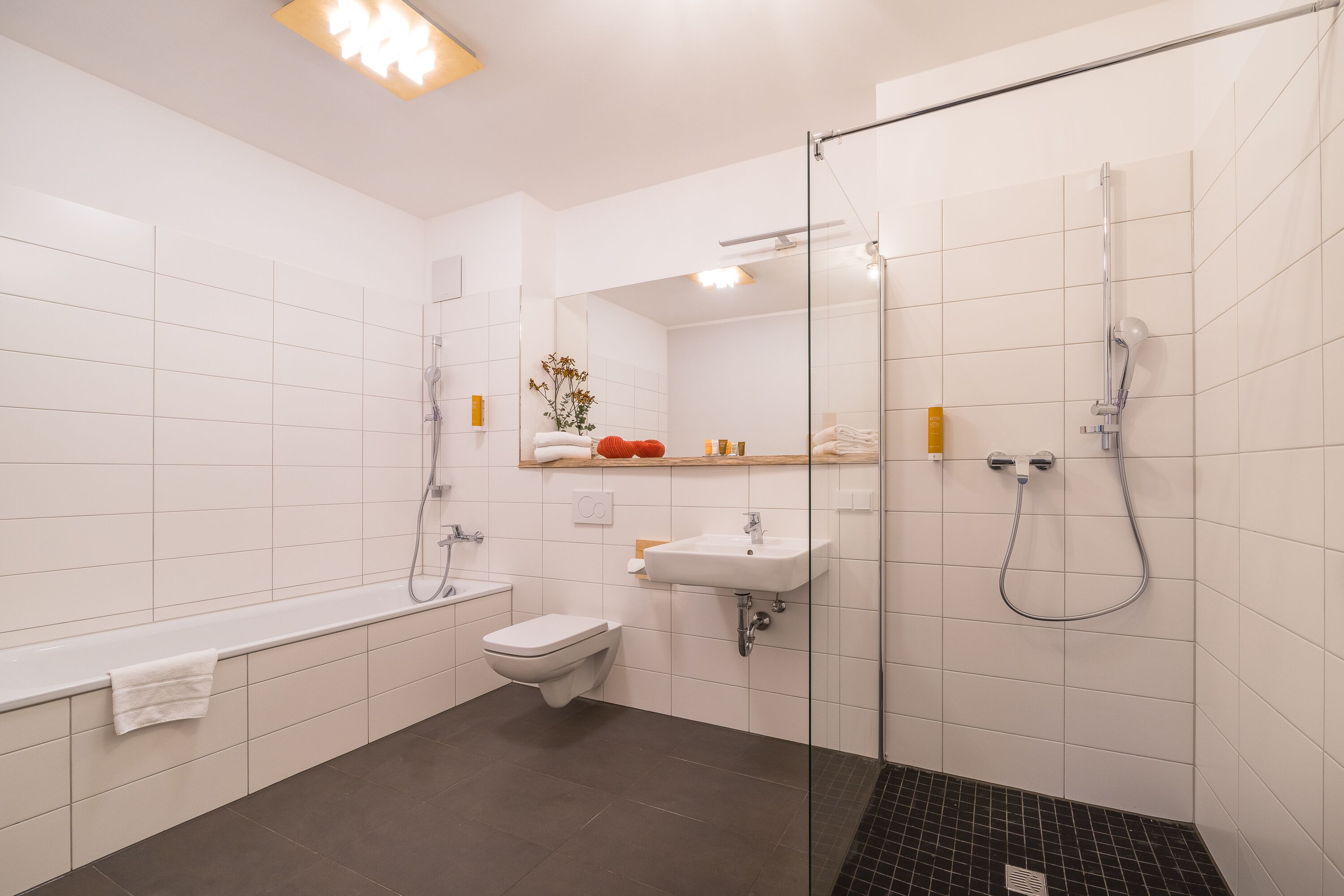 A modern bathroom with a glass-enclosed shower, a white sink, a toilet, and a bathtub.