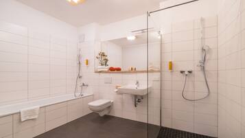 A modern bathroom with a glass-enclosed shower, a white sink, a toilet, and a bathtub.