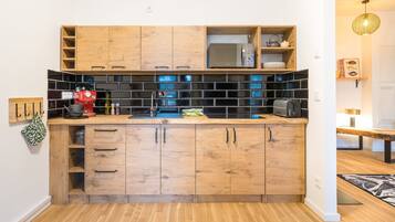 Una cocina compacta con armarios de madera, un salpicadero de azulejos negros y una pequeña encimera.