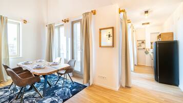 Un coin repas avec une table dressée pour six personnes, un plancher en bois et un tapis à motifs.