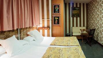 Habitación de hotel con una cama grande, una mesita pequeña, una silla y paredes a rayas.