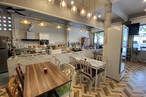 A modern kitchen with a central island, pendant lighting, and a dining area with white chairs. - Hostel Lemon Siam Petchaburi Road (Bangkok)