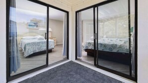 Quarto com duas camas, cada uma com colcha de padrão diferente, e uma grande porta de vidro deslizante que dá para outro cômodo.