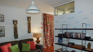 A modern living room with a sofa, a bookshelf, and decorative items. - Oporto Sky Hostel (Porto)