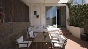 A sunlit outdoor seating area with a wooden table and chairs, a sofa, and potted plants. - Oporto Sky Hostel (Porto)