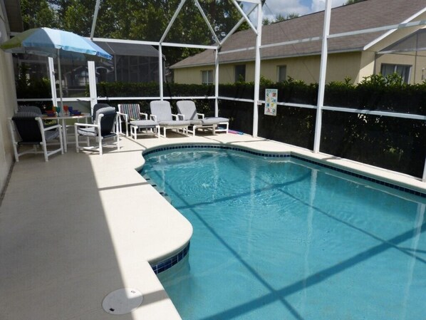 A covered outdoor swimming pool with lounge chairs and a table. - Tm148or (Davenport)