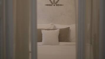 Een slaapkamer met een bed, kussens en een wandlamp.