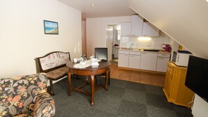 Een compacte leefruimte met een eettafel, een bank en een kitchenette.