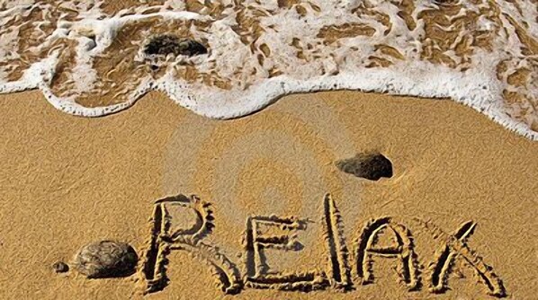 Ein Strand, auf dem das Wort "RELAX" im Sand geschrieben steht.