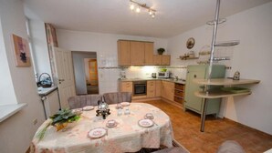 A cozy kitchen with a dining table set for four, wooden cabinets, a microwave, and a sink. - Apartment | 2 people (handicapped accessible) - main building (Carolinensiel)