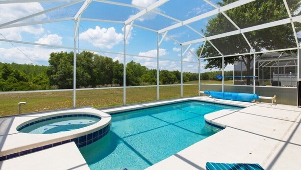 A covered outdoor swimming pool with a hot tub, surrounded by a white canopy structure.