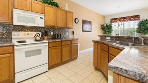 A kitchen with wooden cabinets, a white stove, a microwave, and a tiled backsplash.