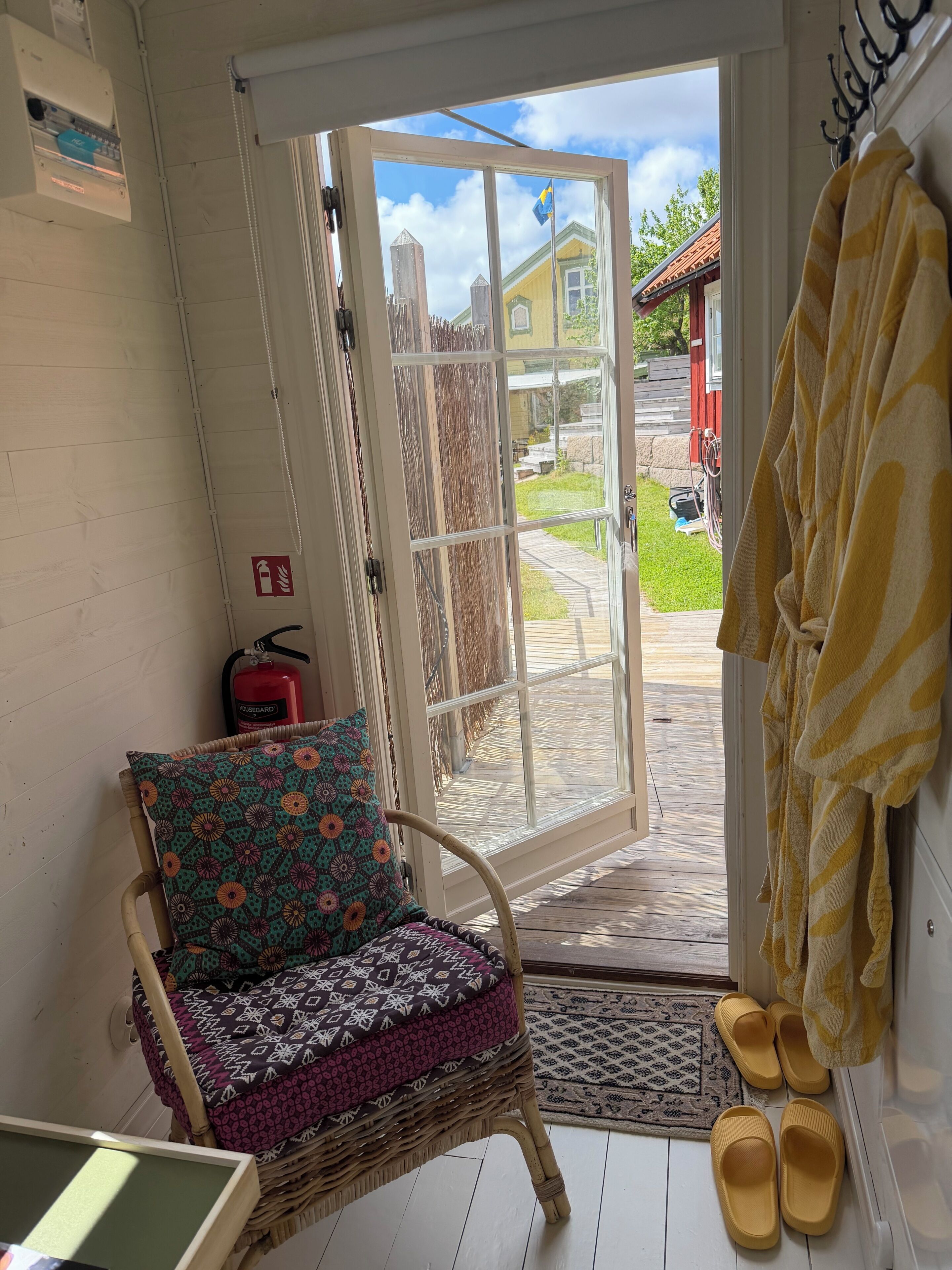 A wicker chair with a patterned cushion, a yellow towel, and a pair of yellow slippers on the floor.