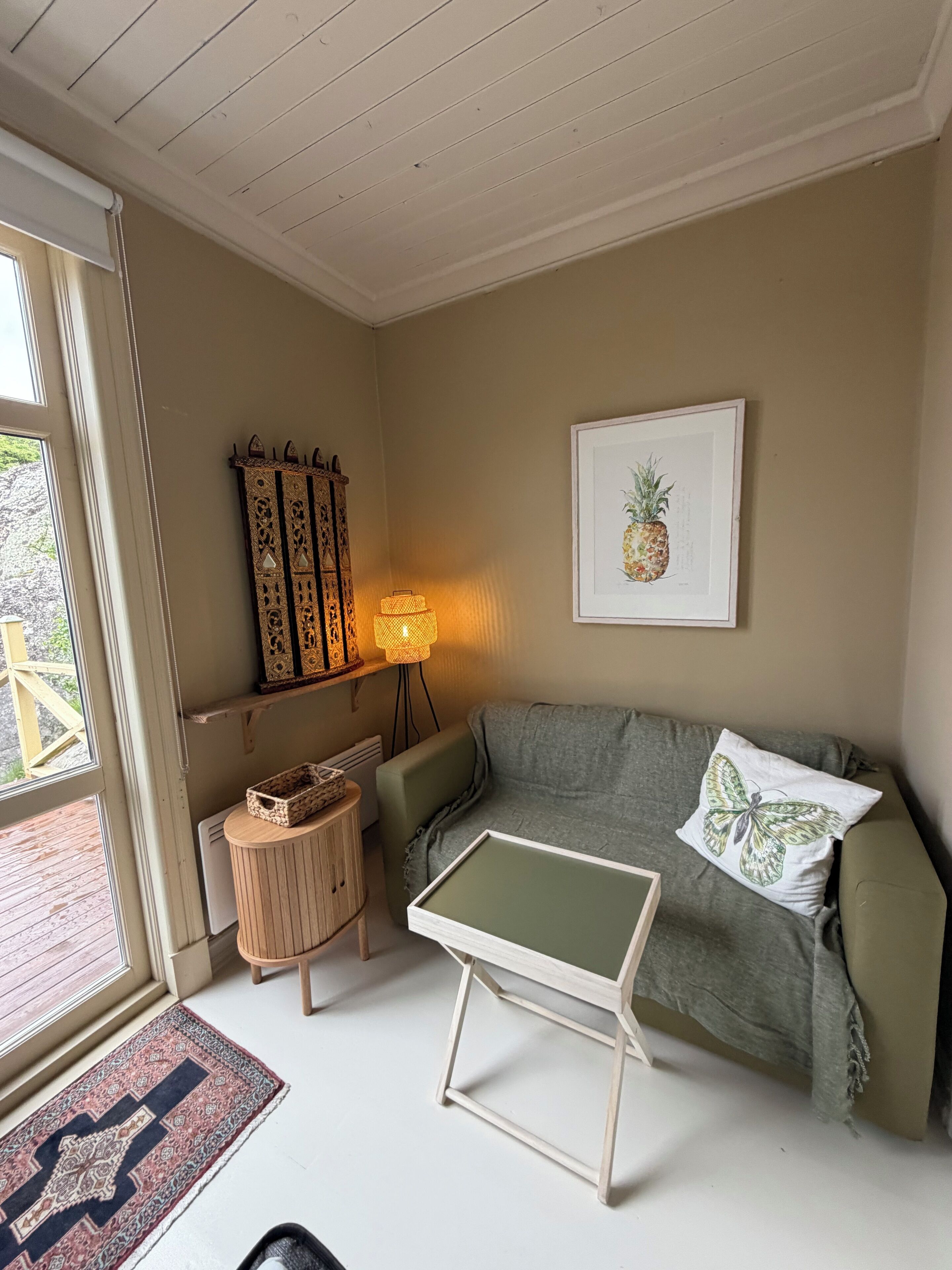 A living room with a sofa, a small table, a lamp, a decorative cabinet, and a framed picture on the wall.