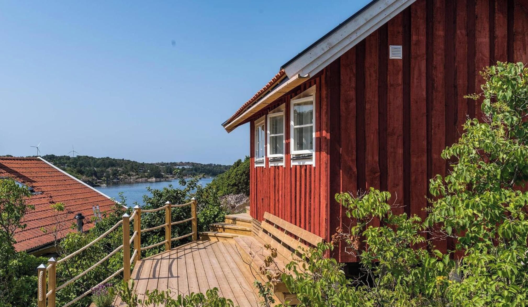 A red wooden building with a wooden deck and a view of a lake and hills.