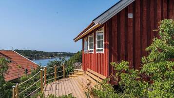 A red wooden building with a wooden deck and a view of a lake and hills.