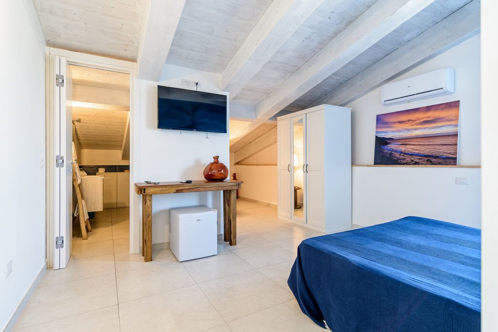 Una camera da letto con un letto, un tavolino, una TV e un quadro appeso al muro.