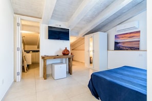 Un dormitorio con cama, una mesita, un televisor y un cuadro en la pared.