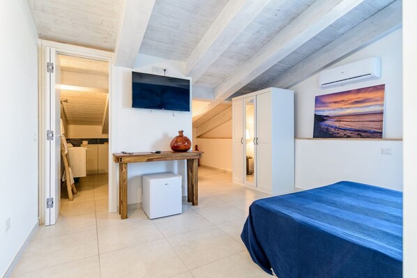 Una camera da letto con un letto, un tavolino, una TV e un quadro appeso al muro.