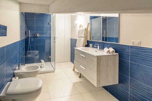 Ein Badezimmer mit Dusche, Toilette und Waschtisch mit Spiegel.