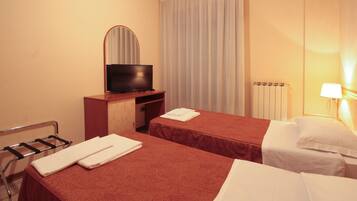 Habitación de hotel con dos camas, televisión, lámpara y radiador.