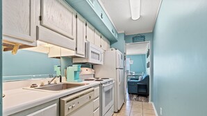 A kitchen with white cabinets, a microwave, a refrigerator, and a sink. - Recently Renovated Oceanfront Condo in Windy Hill + Free Attraction Tickets! (North Myrtle Beach)