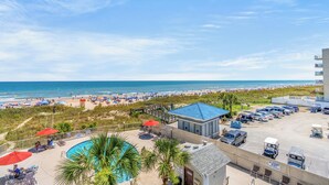A hotel with a pool, beach view, and parking area. - Recently Renovated Oceanfront Condo in Windy Hill + Free Attraction Tickets! (North Myrtle Beach)
