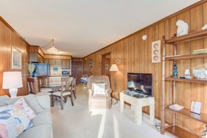 Una sala de estar acogedora, con paneles de madera, un comedor, televisor y estantería.