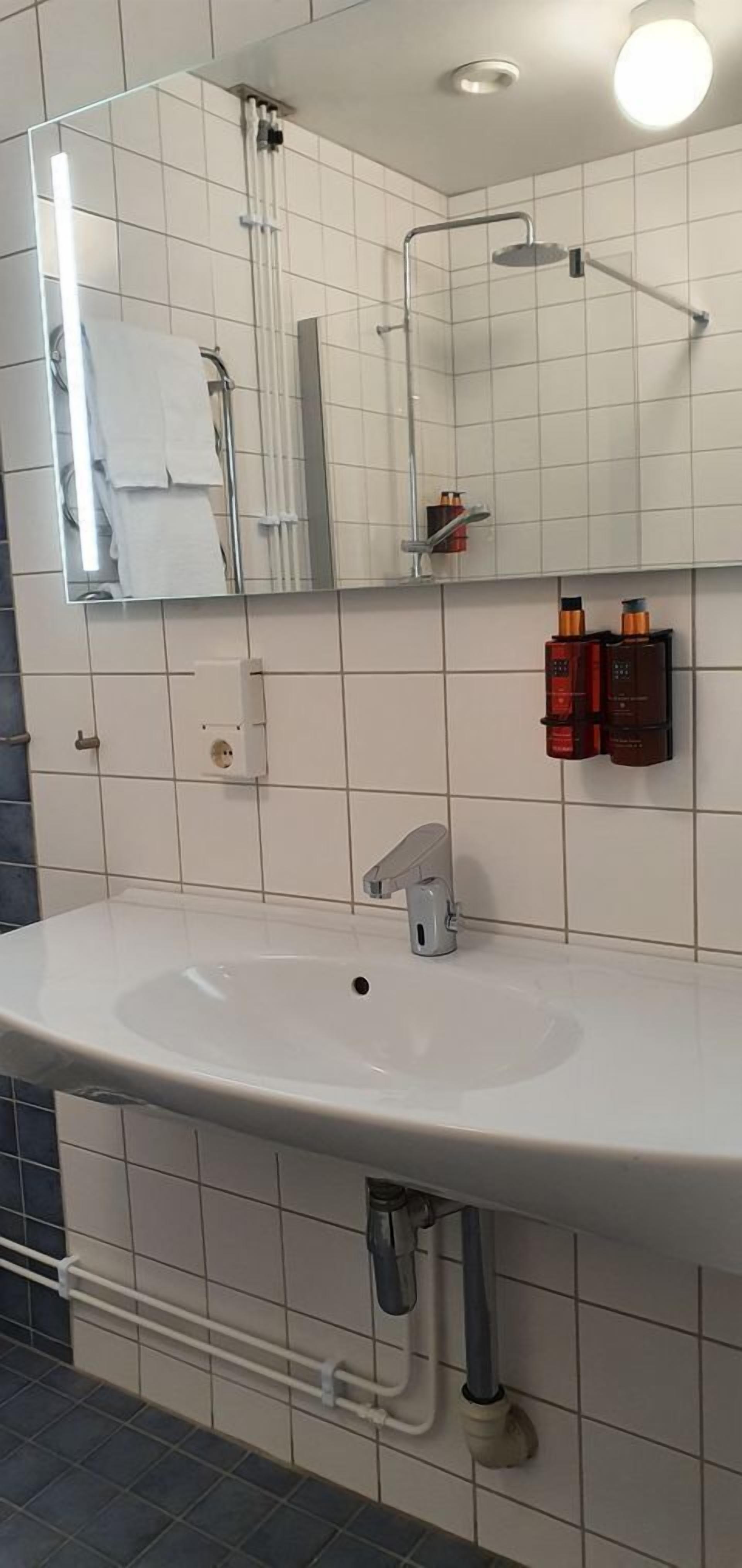 Een badkamer met een witte wastafel, een spiegel en een handdoekhouder.