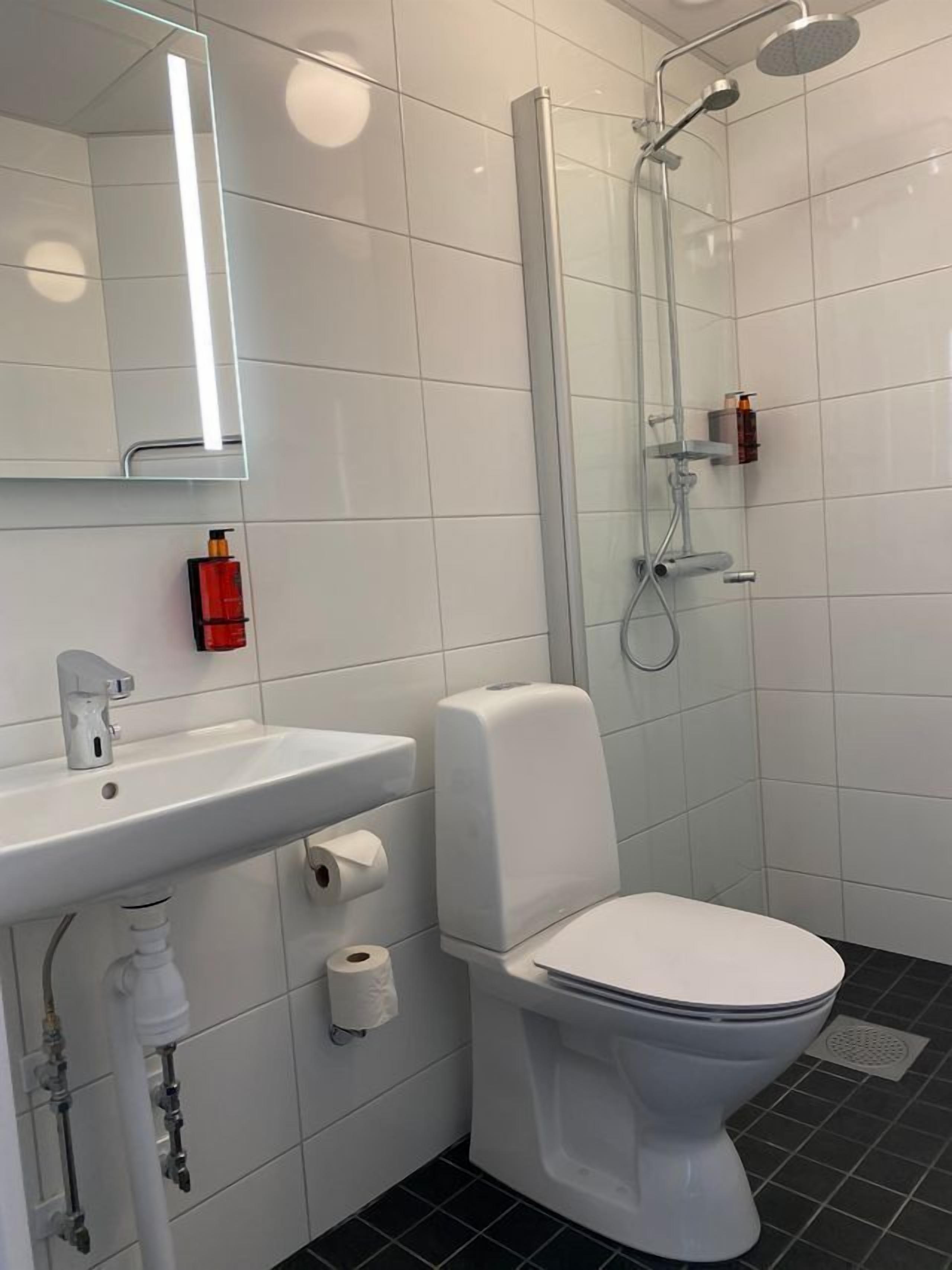 Ein modernes Badezimmer mit Toilette, Waschbecken mit Spiegel und Dusche.
