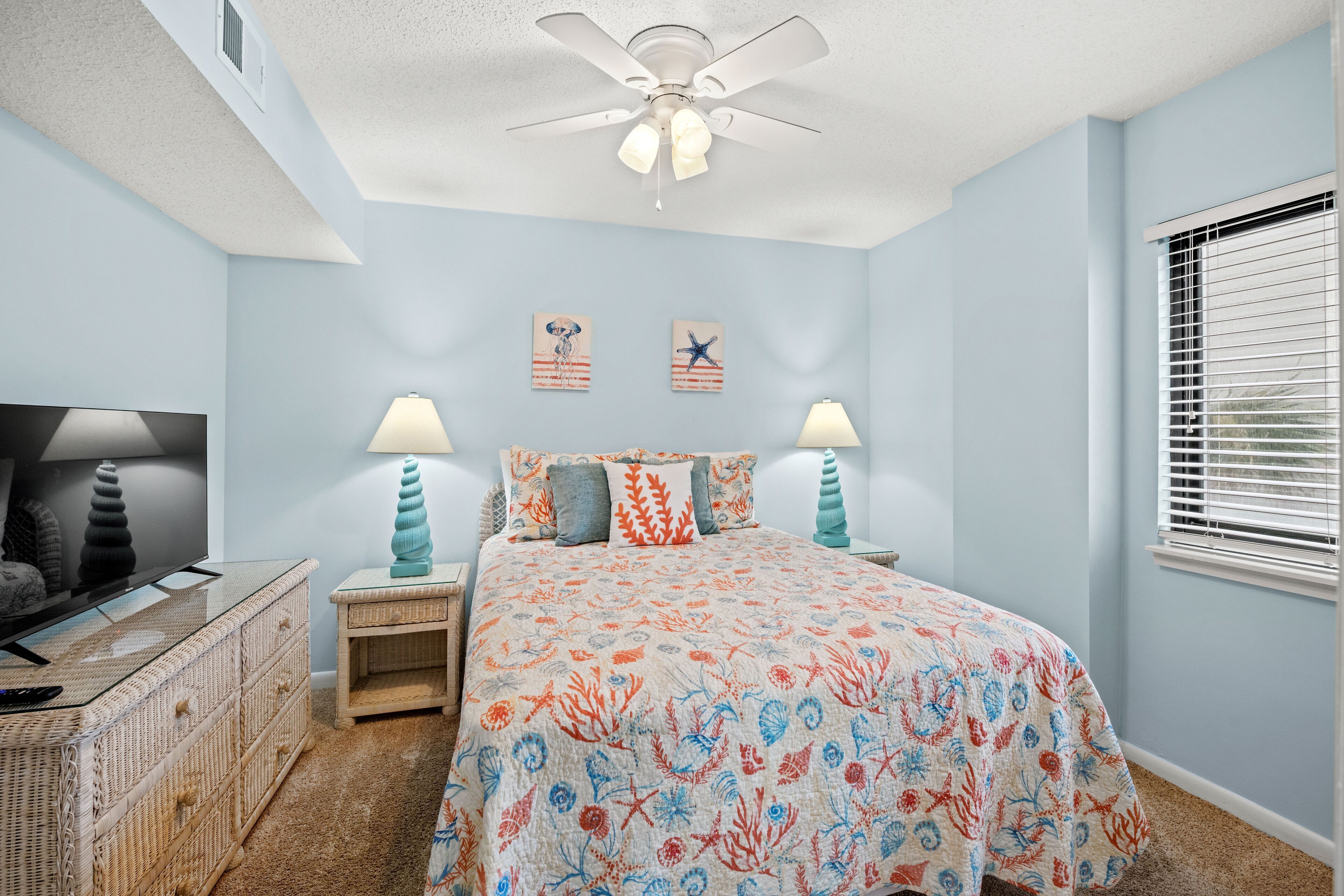 Una camera da letto con un letto, comodini, una ventola a soffitto e decorazioni alle pareti.