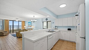 A modern kitchen with white cabinets, a large island, and a view to the outside. - Spacious 1st floor corner Oceanfront unit + Free Attraction Tickets! (North Myrtle Beach)