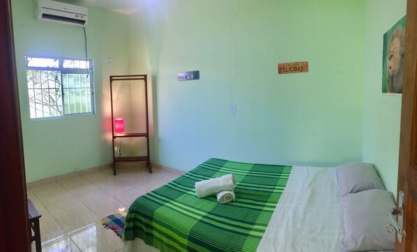 A room with a bed, a standing lamp, a welcome sign, and a window with bars. - Casa Centro Histórico (Paraty)