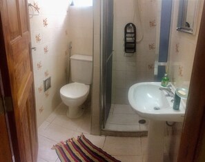 A bathroom with a toilet, shower, and sink. - Casa Centro Histórico (Paraty)