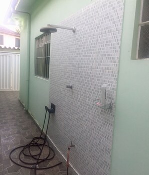 A tiled shower area with a hose and a metal showerhead. - Casa Centro Histórico (Paraty)