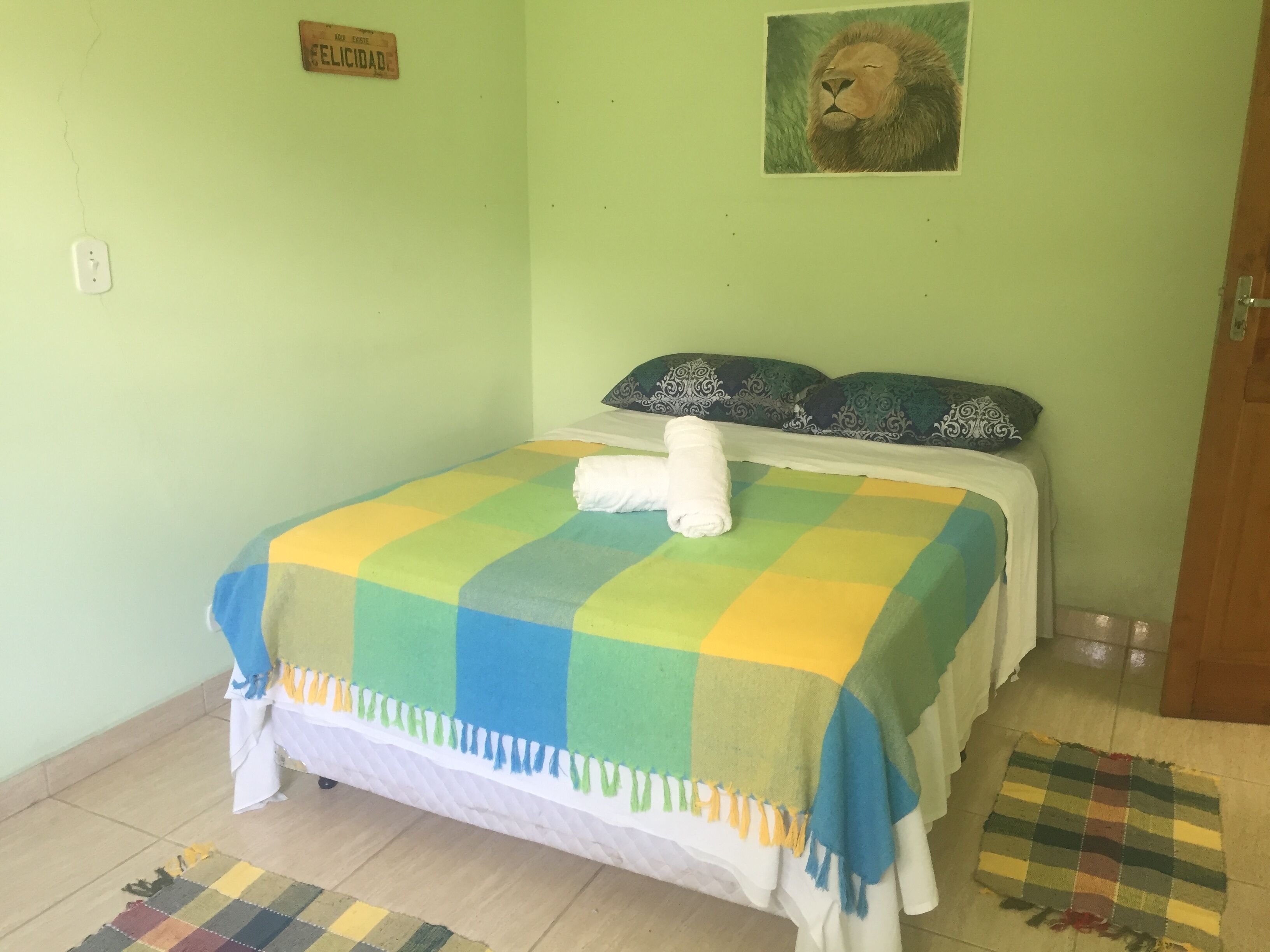 A room with a bed, a wall clock, a framed picture, and a sign on the wall.