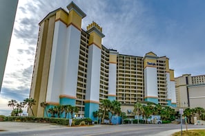 Un hotel grande con varios pisos, un llamativo letrero de 'Bank of the West' y palmeras en primer plano.