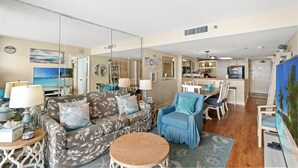 Un salon comprenant un canapé, des fauteuils, une table basse et un coin repas avec des chaises et une table.