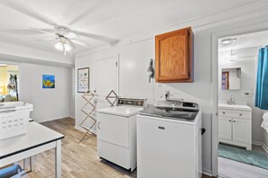 A laundry room with a ceiling fan, a washing machine, a dryer, and a wooden cabinet. - Pet Friendly Oceanfront Duplex (bottom floor) + Free Attraction Tickets! (North Myrtle Beach)