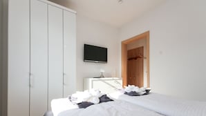A hotel room with two beds, a TV, a wardrobe, and a desk with a lamp. - Well-kept apartment in Greetsiel (Greetsiel)