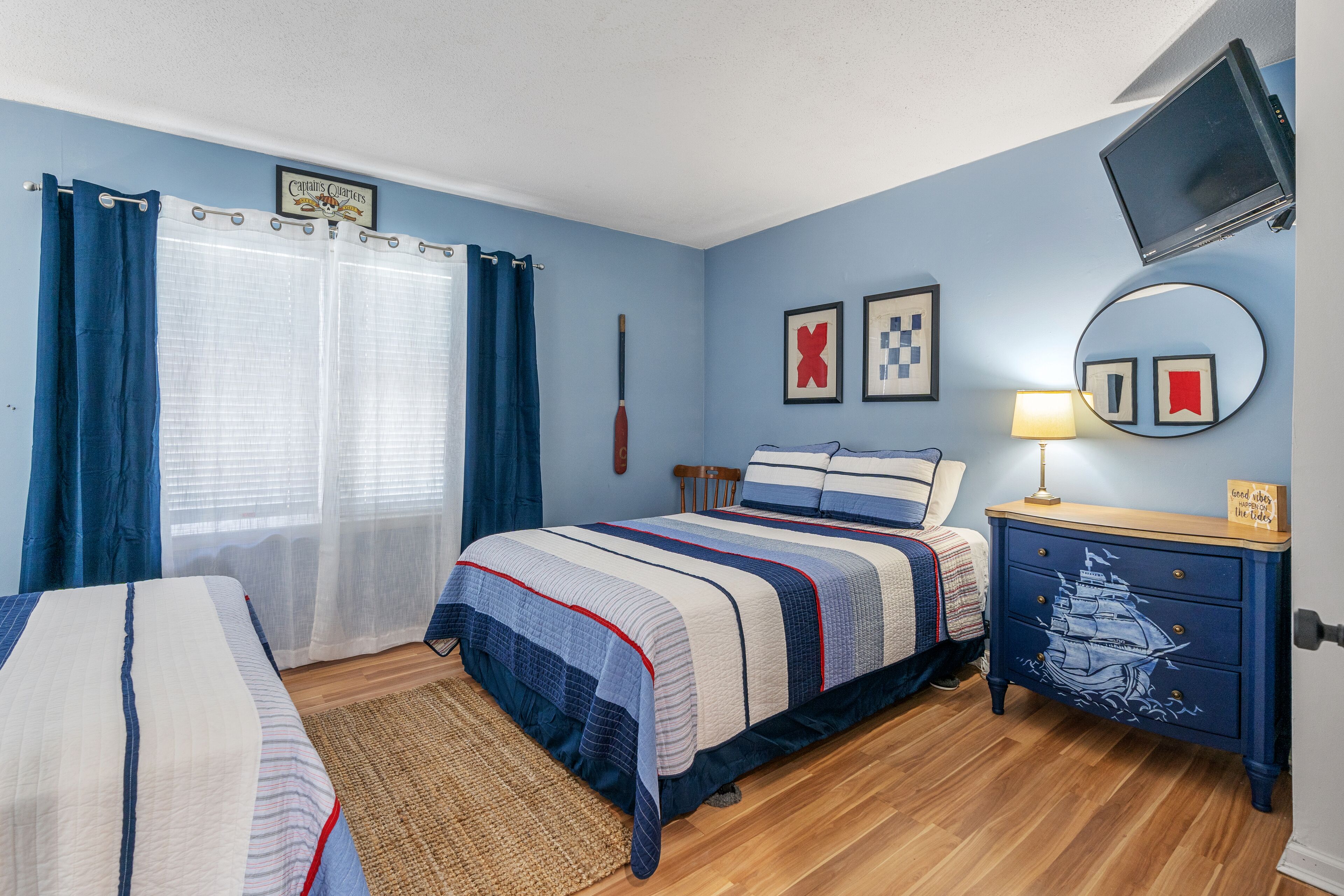 A bedroom with a bed, a nightstand, a mirror, and a TV.
