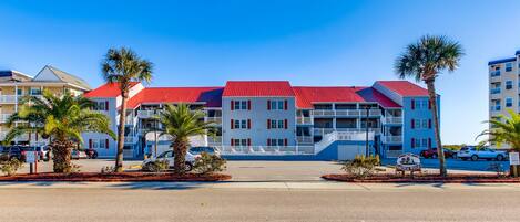 A multi-story hotel with a red roof, white walls, and balconies.