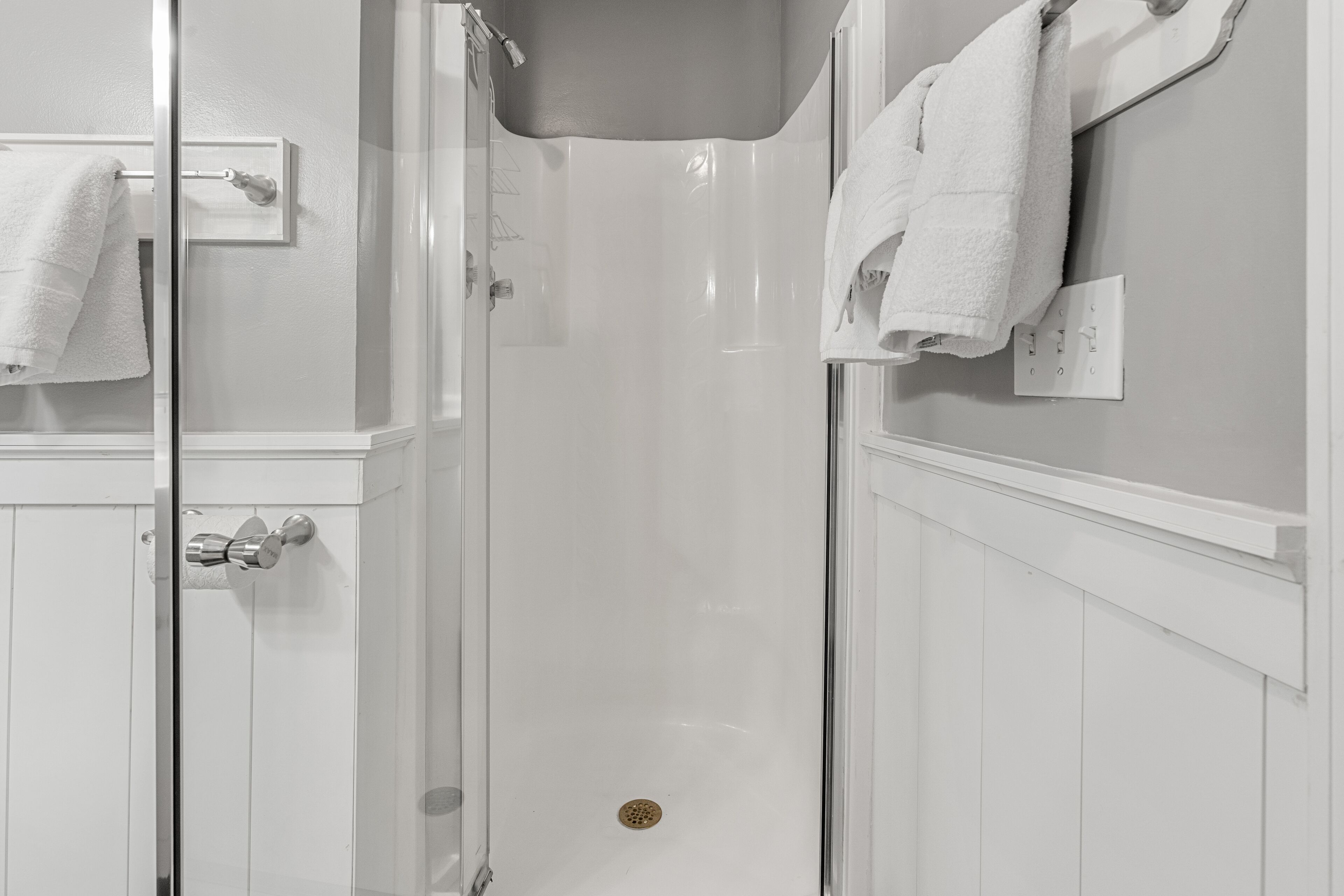 Ein Badezimmer mit einer gläsernen Dusche, weißen Wänden und einem weißen Handtuchhalter.