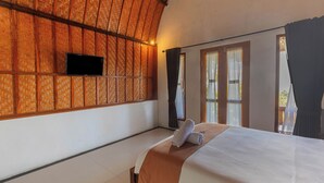 A room with a bed, a television mounted on the wall, and a window with curtains. - Ramp Cottage (Penida Island)