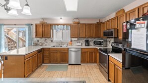 A modern kitchen with wooden cabinets, stainless steel appliances, and a central island. - Pet Friendly Newly Updated Home + Free Attraction Tickets! (North Myrtle Beach)